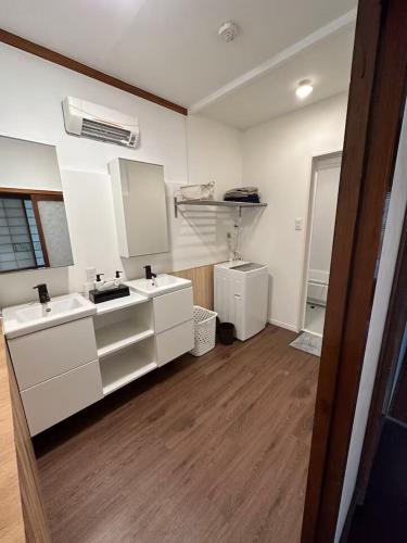 a kitchen with white cabinets and a wooden floor at Kujukuri SHICHIFUKU in Hasunuma