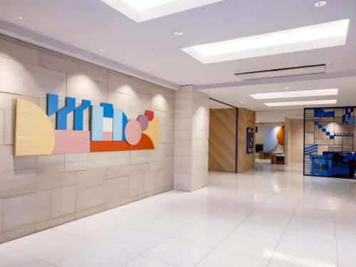 an office lobby with a painting on the wall at ibis Budget Osaka Umeda in Osaka
