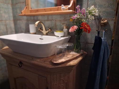 a bathroom with a sink and a vase of flowers at Pacsirta Porta in Nemesnép