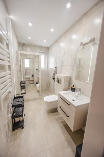 a white bathroom with a sink and a toilet at Przystań Hartowiec in Ostaszewo