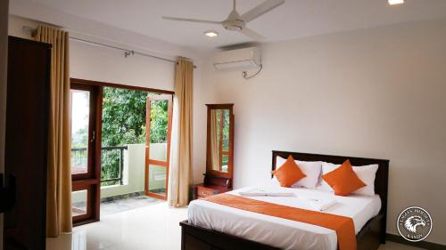 a bedroom with a bed with orange and white pillows at Eagles Hideout Kandy in Bowala
