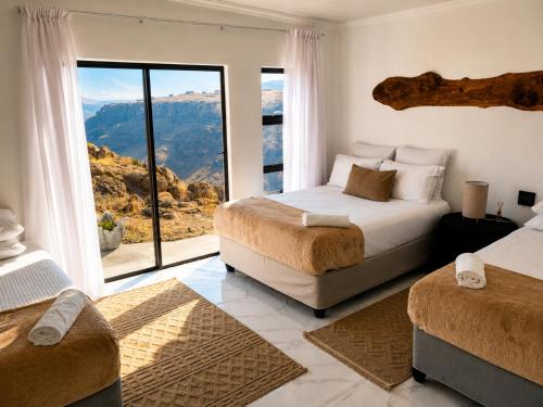 a bedroom with two beds and a large window at 1010 On The Edge in Mokhotlong
