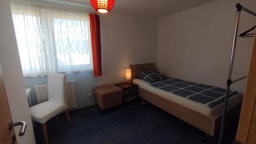 a bedroom with a bed and a chair and a window at Gästehaus mit 3 separaten Schlafbereichen, Terrasse und Carport in Velten