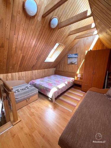 a attic room with a bed and a ceiling at Kotedžiukai Šventojoje in Šventoji