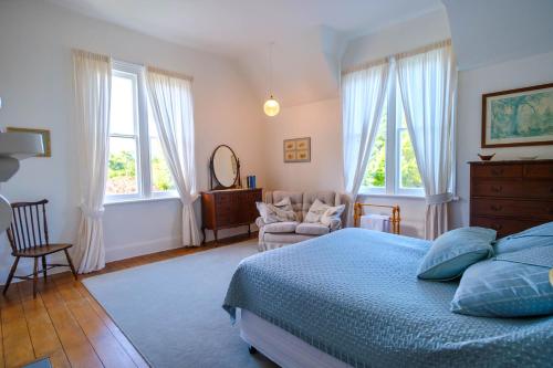 a bedroom with a bed and a chair and windows at Waikonini Homestead in Geraldine