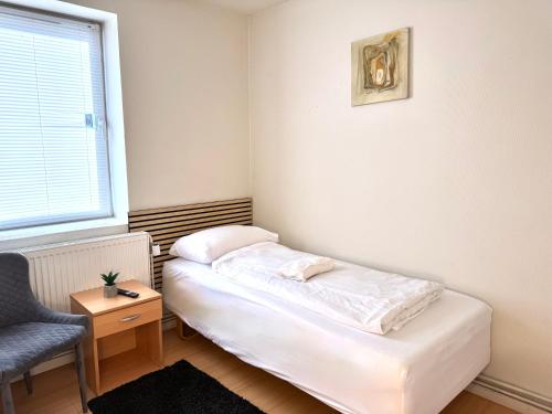 a small room with a bed and a chair at Padborg Inn - Simple Rooms & Modern Apartments in Padborg