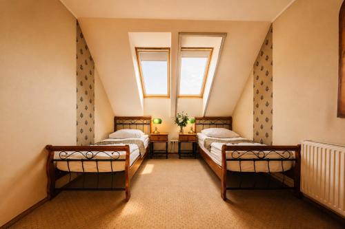 two beds in a attic room with a window at Stara Szkoła Boutique Hotel in Wronki