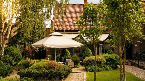 a person sitting under an umbrella in a garden at Stara Szkoła Boutique Hotel in Wronki