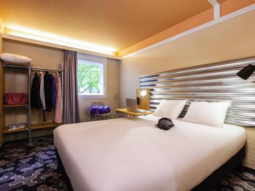 a large white bed with a hat on top of it at Ibis Styles Bobigny Centre Préfecture in Bobigny