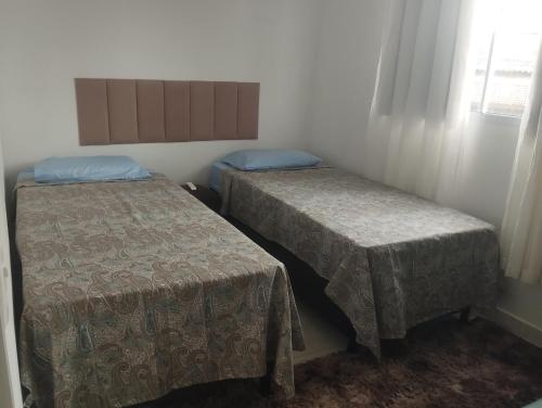 a room with two beds and a window at Apartamento porto dos mares in Salvador