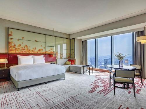 a hotel room with a bed and a large window at Pullman Huizhou Kaisa in Huizhou