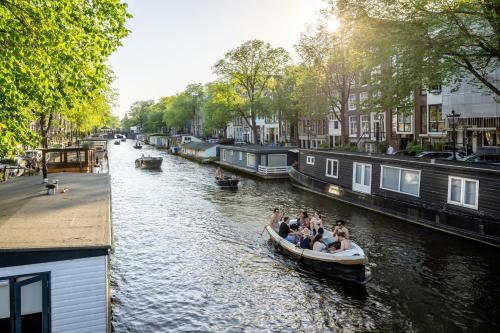 a group of people riding in a boat down a canal at Hotel Prinsenhof Amsterdam in Amsterdam