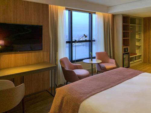a hotel room with a bed and a large window at Mercure Itajai Navegantes in Itajaí