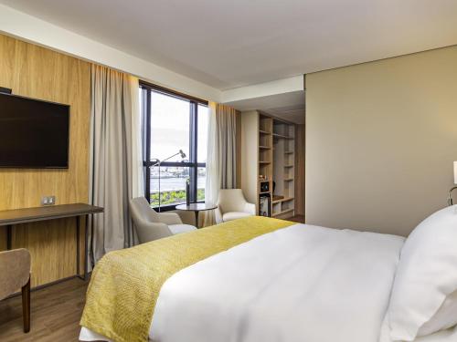 a hotel room with a bed and a television at Mercure Itajai Navegantes in Itajaí