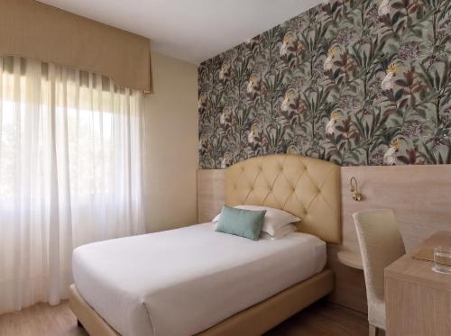 a bedroom with a bed with a floral wallpaper at Hotel Castello Artemide Congressi in Castel San Pietro Terme