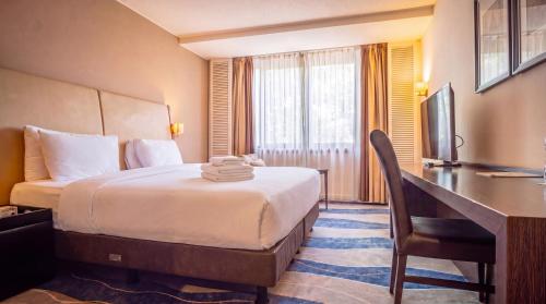 a hotel room with a bed and a desk at Lancaster Accra in Accra