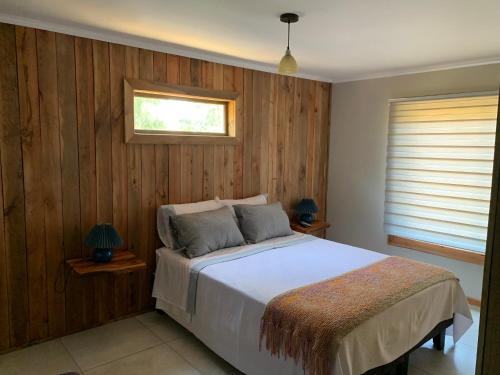 a bedroom with a bed with wooden walls and a window at Viejo Boldo hotel y cabañas in Curepto