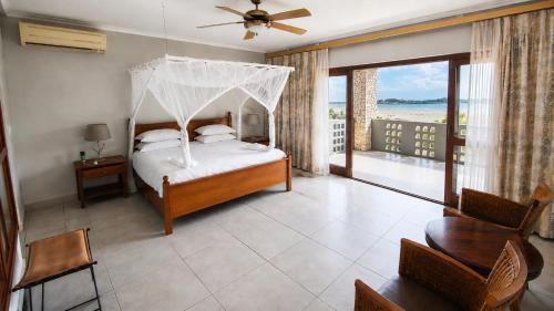 a bedroom with a canopy bed and a balcony at Giney's View 8 Unit in Vilanculos