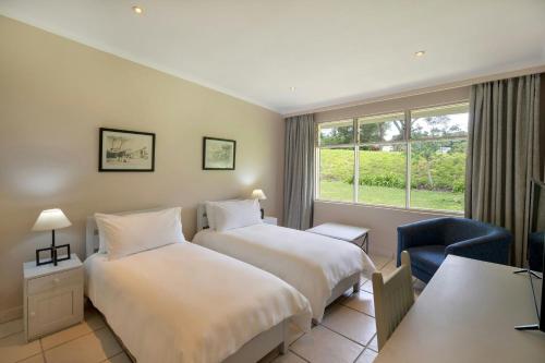 a hotel room with two beds and a window at Protea Hotel by Marriott Chingola in Chingola