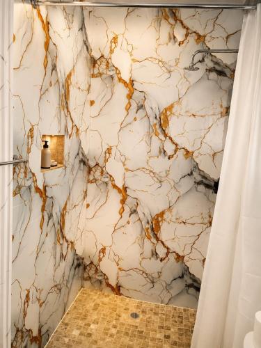a bathroom with a marble wall with a shower curtain at 1010 On The Edge in Mokhotlong