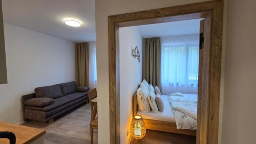 a bedroom with a bed and a couch and a mirror at Apartmán Mlýn 208 in Vrchlabí