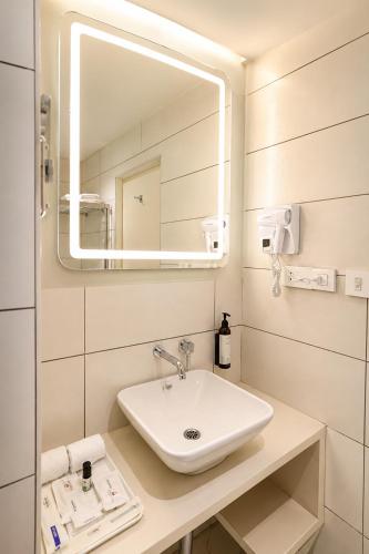 a bathroom with a sink and a mirror at The Arcadia Coimbatore Airport in Coimbatore
