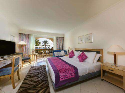 a hotel room with a bed and a television at Movenpick Resort Taba in Taba