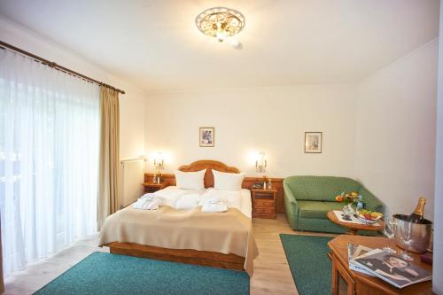 a hotel room with a bed and a green chair at Alpenhof Grainau in Grainau