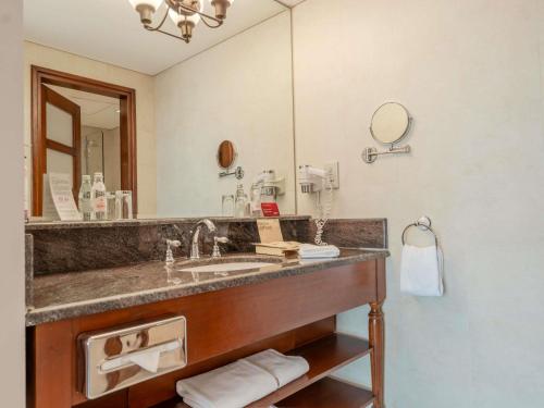 a bathroom with a sink and a large mirror at Mövenpick Hotel & Resort Al Bida'a in Kuwait