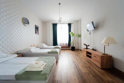 a hotel room with three beds and a tv at Apartament Kutno - Sami Swoi in Kutno