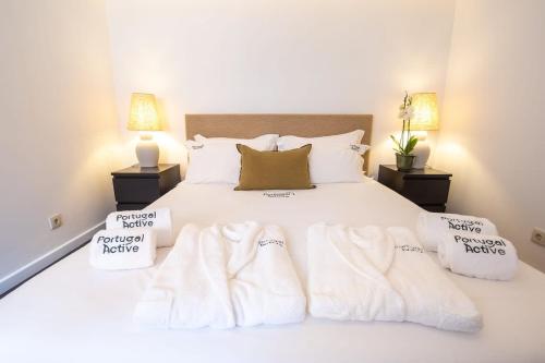 a bedroom with a white bed with towels on it at PortugalActive Beach Flat in Viana do Castelo
