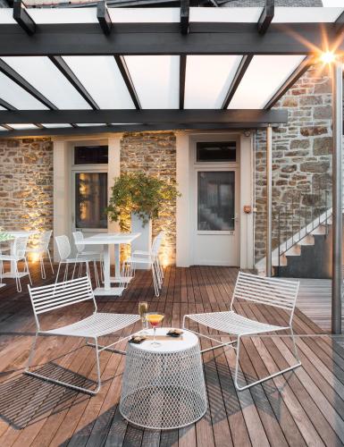 a patio with white chairs and tables and a brick wall at Hotel Eden in Saint Malo