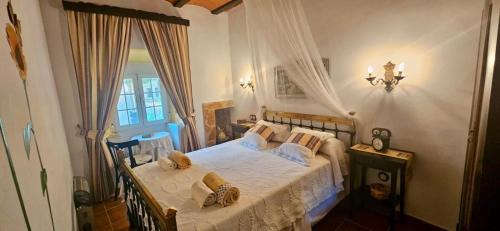 a bedroom with a bed with white sheets and a window at Casa Turística Los Girasoles 