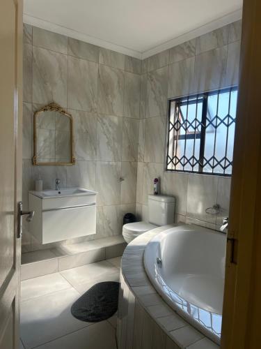 a white bathroom with a tub and a sink at Piink Lopez in Manzini