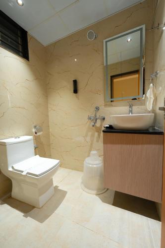 a bathroom with a toilet and a sink and a mirror at Dlite Rivera Premium Hotel Apartments in Bangalore
