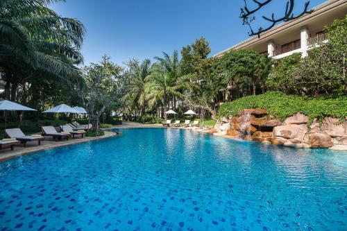 a swimming pool with chairs and a resort at Ravindra Beach Resort & Spa - SHA Extra Plus in Na Jomtien