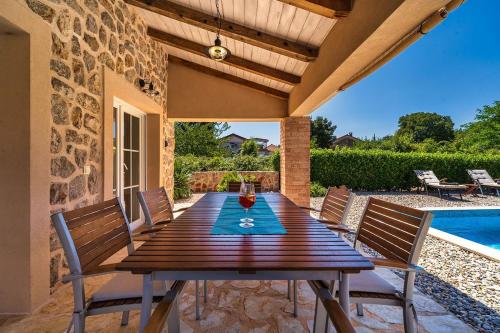 a wooden table and chairs on a patio with a pool at Villa Pepina in Risika