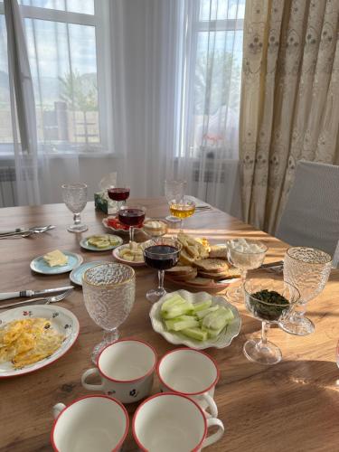 a wooden table with plates of food and wine glasses at Kochkor valley in Kochkorka