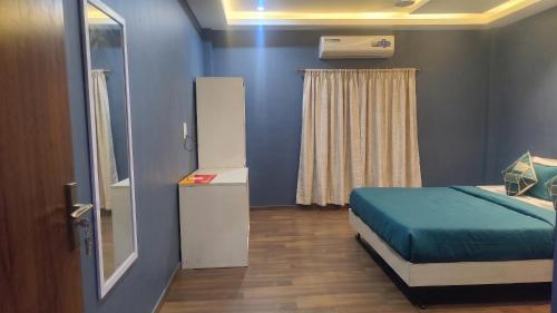 a blue room with a bed and a window at FabHotel Elite Residency in Vasai