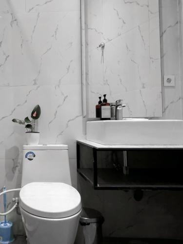 a white bathroom with a toilet and a sink at Edy's Farm Cottage in Jabon