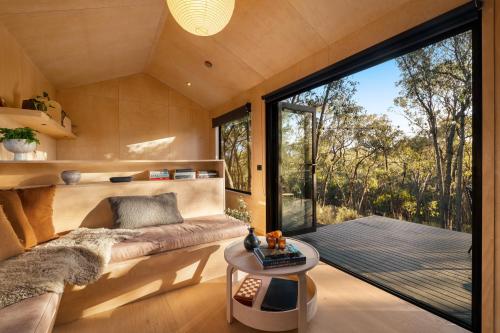 a living room with a couch and a large window at HeartStone Hill - Tiny House in Castlemaine