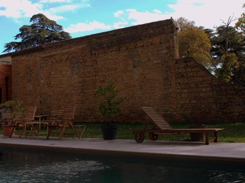 two chairs and a picnic table next to a brick wall at Effet Lodge in Saint-Cyr-au-Mont-dʼOr