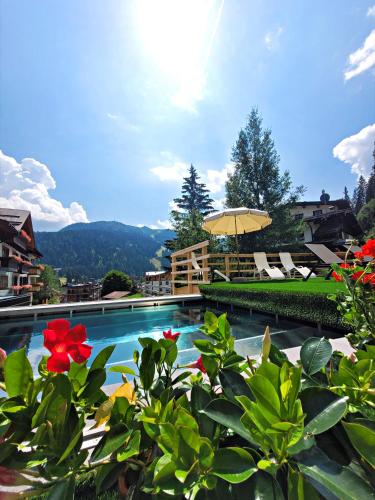 a swimming pool with flowers and an umbrella at Hotel Dahu in Madonna di Campiglio