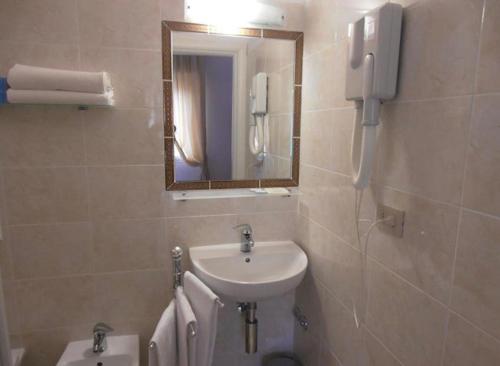 a bathroom with a sink and a mirror and a toilet at Hotel Toscana in Marotta