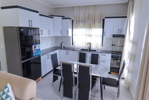 a kitchen with white cabinets and a table and chairs at Zeus Boutique Apartment in Kigali