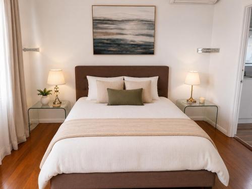 a bedroom with a large bed with two lamps at Stunning Sea Facing Bayside House with Pool in Birkdale