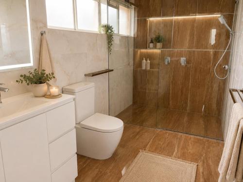 a bathroom with a shower and a toilet and a sink at Stunning Sea Facing Bayside House with Pool in Birkdale