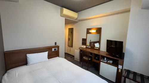 a hotel room with a bed and a desk with a television at Hotel Route-Inn Gotenba Eki-Minami in Gotemba