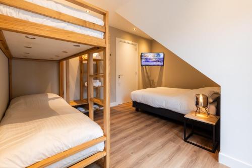 two bunk beds in a room with a tv at Veluwe Villa with Indoor Pool & Wellness | 12 persons in Wekerom
