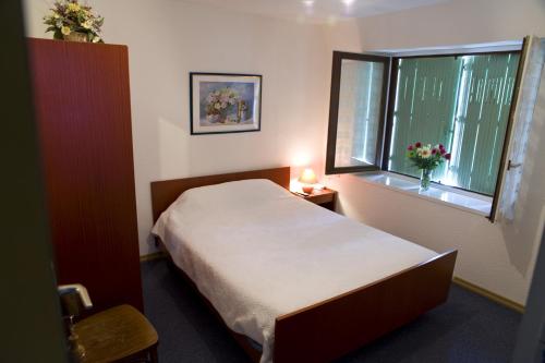 a small bedroom with a bed and a window at L'Auberge Fleurie in Le Nayrac